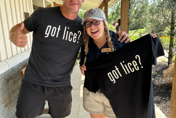 How to check for head lice at summer camp - Pete the Lice Guy and a camp nurse smiling while holding a 'got lice?' t-shirt.